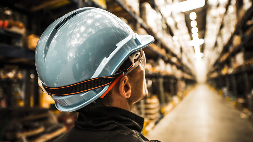 man-wearing-safety-helmet-and-safety-glass-standing-at-modern-warehouse