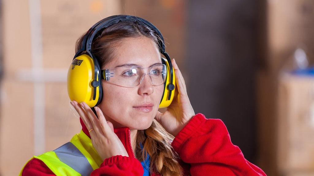 Woman wearing a custom printed safety vests wearing hearing protection